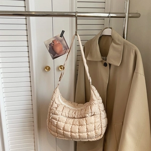 Vista dettagliata della borsa a spalla trapuntata beige con tasca a zip su supporto