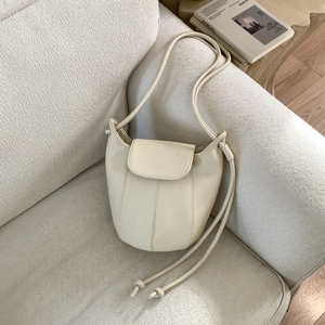 Detailed view of cream leather bucket bag with pebble texture on a soft sofa