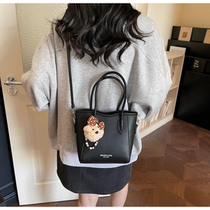 Détail du sac seau noir avec texture litchi et petit ours en peluche