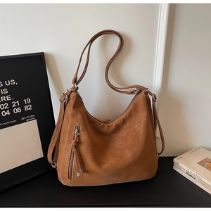 Detail of brown faux suede hobo bag featuring vertical zipper pocket and tassel charm