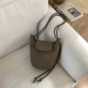 Detailed macro view of taupe lychee leather texture and stitching on the bucket bag