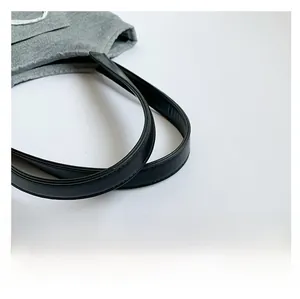 Detailed close-up of soft black leather straps on a grey textured fabric bucket handbag