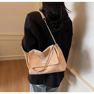 Dettaglio della borsa tote in pelle scamosciata albicocca con accenti metallici e catena