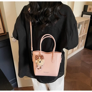 Détails de la texture du cuir litchi rose du sac seau avec un pendentif ours en peluche