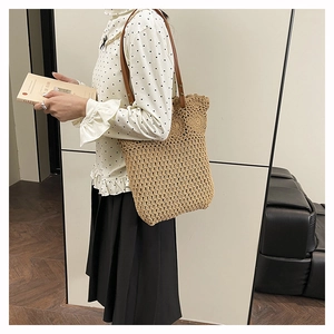Gros plan d'un sac cabas en paille ajouré beige avec des anses en cuir marron chic