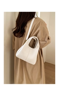 Detail of white litchi grain leather bucket bag with golden hardware and adjustable strap