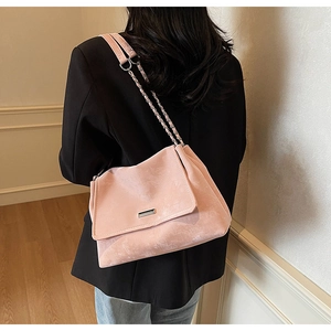 Détail du sac cabas en daim rose doux avec bandoulière chaîne argentée et boucle métal