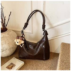 Dettaglio della borsa a spalla vintage marrone scuro in ecopelle con ciondolo a orsetto