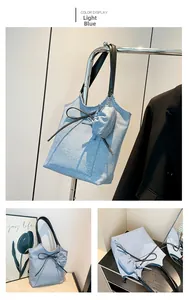 Detail of light blue denim texture tote bag with black handles and decorative bow
