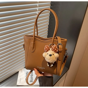 Détail d'un sac seau marron en cuir grainé avec charm ours et logo argenté élégant
