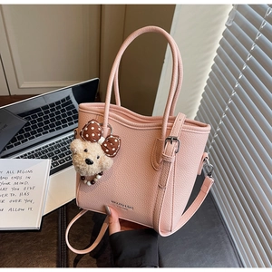 Détail du sac seau rose clair grainé avec breloque d'ours en peluche et poignée