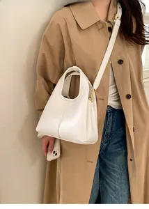 Lifestyle shot of cream white lychee leather bucket bag worn with khaki trench coat