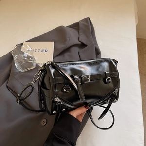 Detailaufnahme der schwarzen Zylinder-Tasche mit Reißverschlüssen und glänzendem Leder