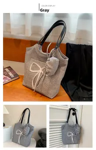 Detail view of a gray knit tote bag with a white lace bow and a mini hanging coin purse