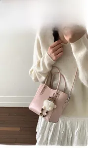 Détail du sac à main en cuir rose avec pendentif en peluche et poignée circulaire