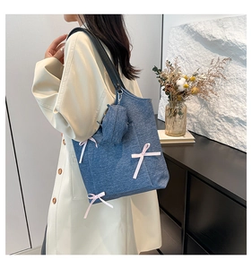 Detail view of blue denim tote bag with pink bows and side mini zipper pouch