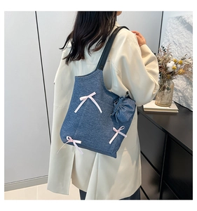Detail of denim blue tote bag featuring pink bows and a mini storage pouch