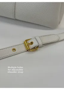 Detail of adjustable white litchi leather shoulder strap with gold buckle and eyelets