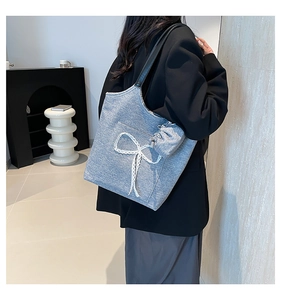 Detail view of denim tote bag with delicate lace bows and leather shoulder strap