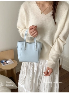 Détail du sac seau bleu clair montrant la texture du cuir synthétique et les poignées