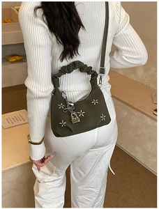 Detail of dark green pleated dumpling bag with silver star rivets and metallic lock charm