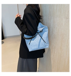Detail shot of light blue tote bag with black drawstring on model in modern setting