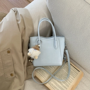 Gros plan d'un sac seau bleu clair avec charme en peluche sur canapé blanc