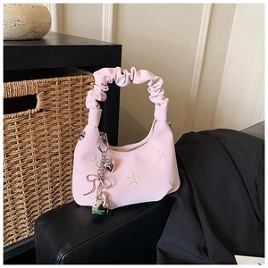 Detailed view of pink pleated handbag with star embroidery and heart charm accessory