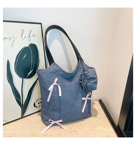 Detail of blue denim tote bag with pink ribbon bows and detachable drawstring pouch