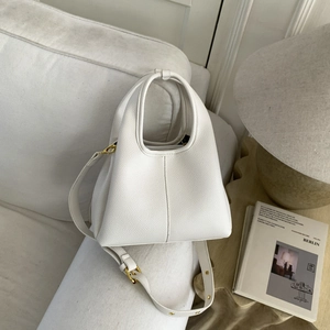Close-up of white lychee pattern leather tote bag with gold hardware in minimalist home decor