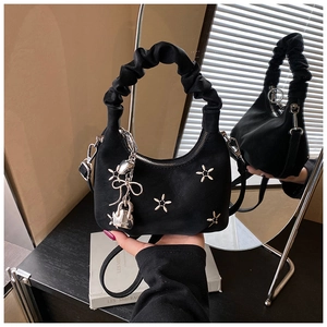 Detail of black pleated dumpling bag featuring star embroidery and silver hardware charms