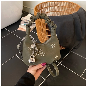 Detail of olive green crescent bag with star studs, ruched handle and fashion charms