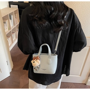 Detail view of light blue lychee pattern leather mini bucket bag with teddy bear charm
