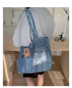 Dettaglio della borsa tote in denim a righe blu con tasca frontale e ciondolo a orsetto