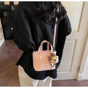 Detail of pink pebbled leather mini bucket bag with teddy bear charm worn by a model