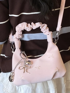 Pink pleated hobo bag with flower embroidery and ruffled handle worn as a crossbody bag