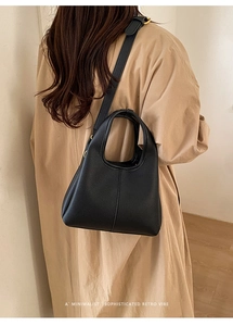Detail of black lychee grain leather handbag featuring adjustable strap and gold hardware