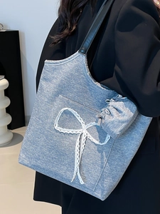 Light blue denim tote bag with lace bow and black shoulder straps on model