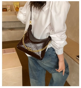 Détail du sac hobo marron foncé brillant avec chaîne dorée épaisse et logo de marque