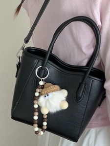 Sac seau élégant en cuir PU noir avec pendentif peluche et chaîne perlée porté par mannequin