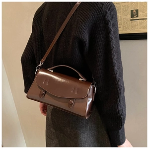 Detail shot of a dark brown vintage crossbody bag featuring a glossy leather finish