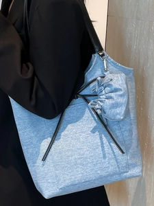 Minimalist light blue denim tote bag with black leather straps and a matching mini pouch