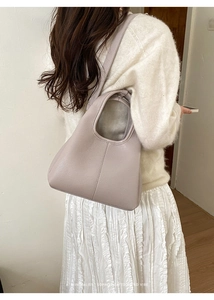 Close-up of minimalist pebble leather tote bag in mauve with sleek curved handle detail