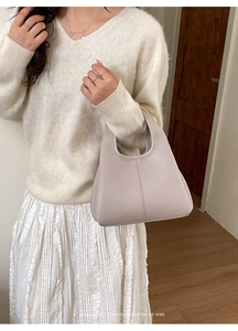 Detail of light purple pebbled leather bucket bag styled with white casual outfit