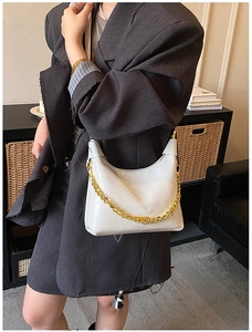 Détail du sac demi-lune en cuir blanc avec chaîne dorée sur un blazer gris chic