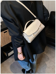 Side view of cream white PU leather baguette bag on a black blazer with stitching details