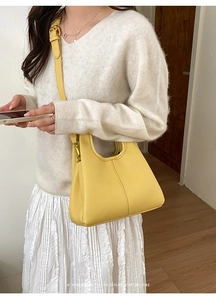 Detail of yellow lychee grain leather hobo bag with adjustable gold buckle and stitching