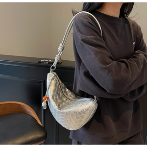 Detail of silver woven hobo bag featuring manual knot strap and orange bead charm