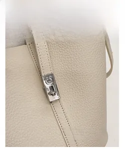 Detailopname van beige lederen emmertas met een elegante zilveren metalen sluiting