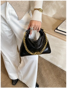 Détail du sac en cuir verni noir brillant avec une chaîne dorée épaisse et couture
